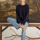 graced navy ribbed cuff sweater worn by a woman with light blue jeans and beige loafers in a rustic setting