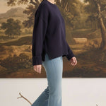 Model wearing a graced navy ribbed cuff sweater with a relaxed fit, paired with light blue flare jeans and loafers.