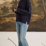 graced navy ribbed cuff sweater worn by a model with light blue jeans in a studio setting