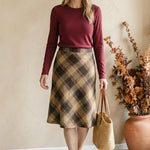 graced wine round neck knit top worn by a woman with a plaid midi skirt and straw tote bag