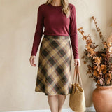 graced wine round neck knit top worn by a woman with a plaid midi skirt and straw tote bag