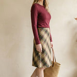 graced wine round neck knit top worn by a woman with a plaid skirt and straw tote bag