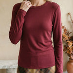 A woman wearing a graced wine-colored long-sleeve round neck knit top with a fitted silhouette.