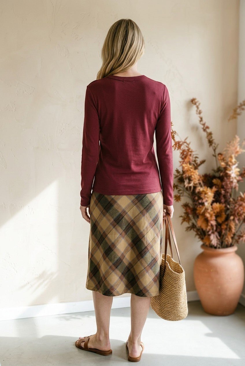 graced wine round neck long sleeve knit top worn with a plaid midi skirt and straw tote bag