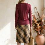 graced wine round neck long sleeve knit top worn with a plaid midi skirt and straw tote bag