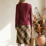 graced wine round neck long sleeve knit top worn with a plaid midi skirt and straw tote bag