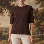 graced espresso brown short sleeve knit top worn by a model with beige trousers against a scenic landscape backdrop
