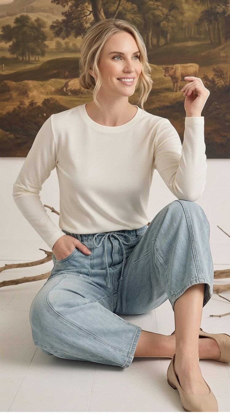 graced model wearing light wash soft denim barrel pants with a drawstring waist and a long-sleeve cream top