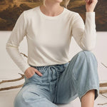 graced model wearing light wash soft denim barrel pants with a drawstring waist and a long-sleeve cream top