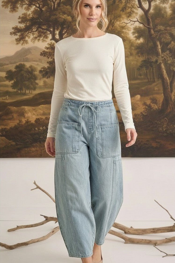 Model wearing graced soft denim barrel pants in light wash cotton with a drawstring waist and large patch pockets.