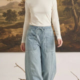 Model wearing graced soft denim barrel pants in light wash cotton with a drawstring waist and large patch pockets.