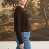 Woman wearing a dark brown textured button down cardigan by graced, paired with blue jeans in a studio setting.