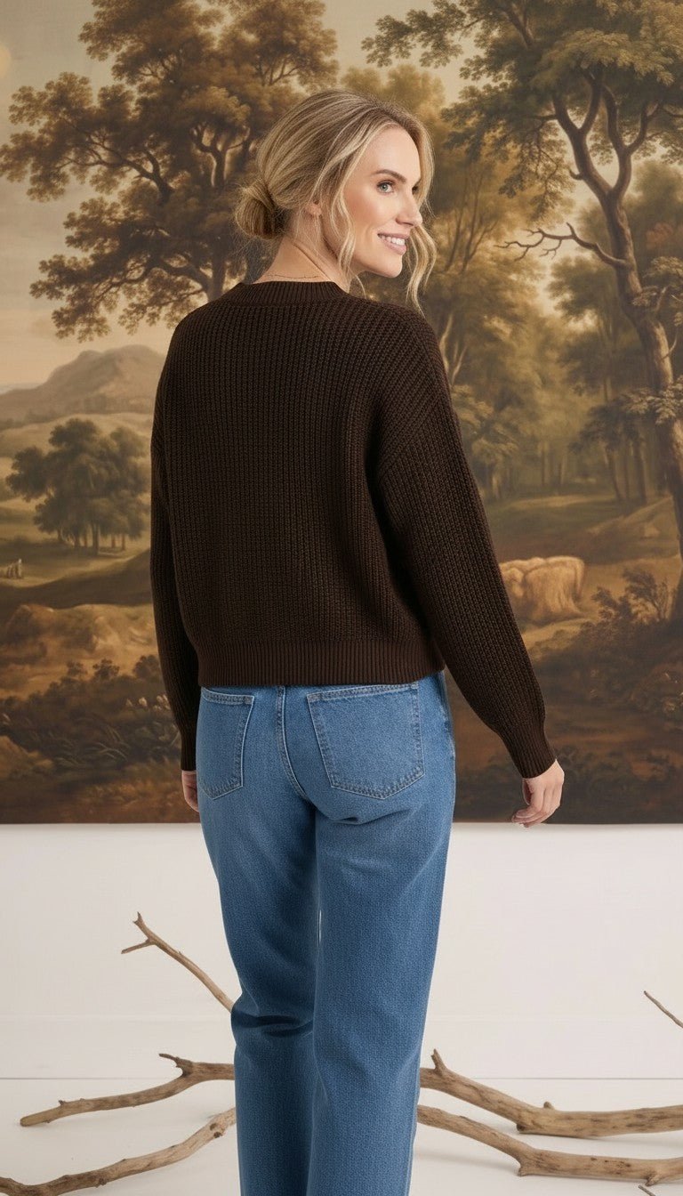 graced textured dark brown button down cardigan worn by a blonde woman with blue jeans, back view