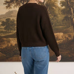 graced textured dark brown button down cardigan worn by a blonde woman with blue jeans, back view