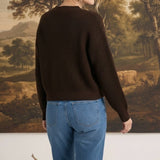 graced textured dark brown button down cardigan worn by a blonde woman with blue jeans, back view
