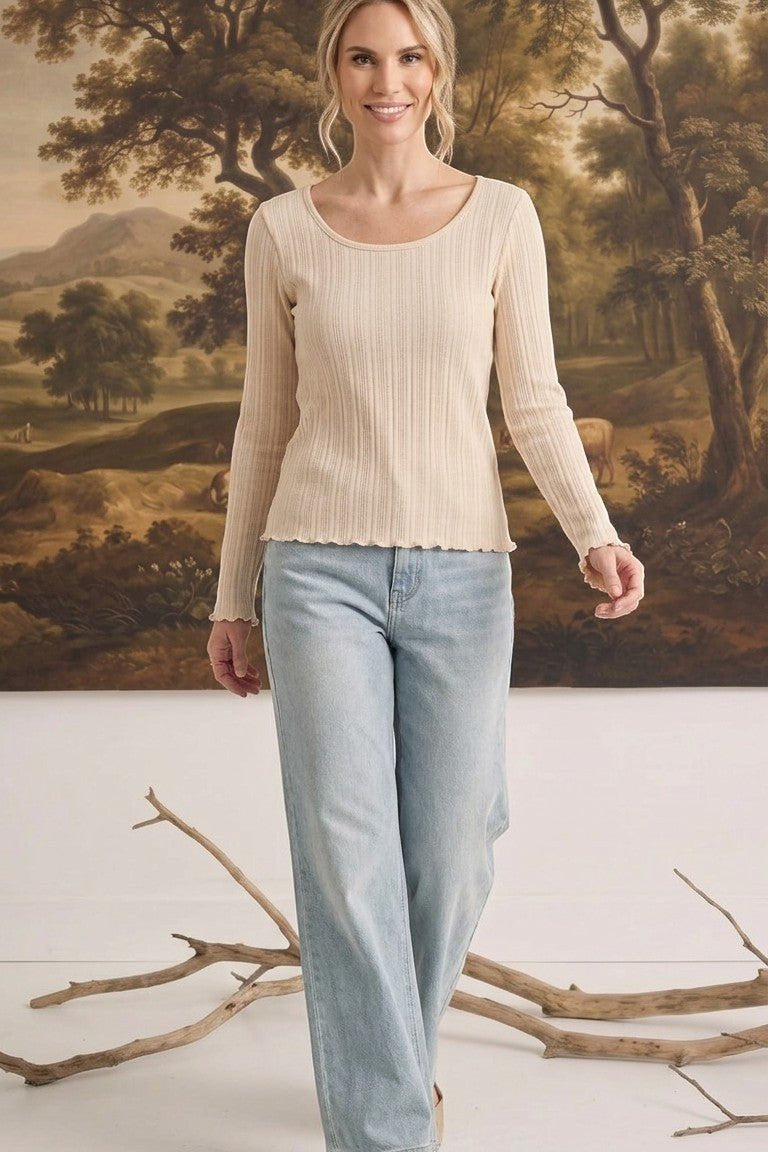 graced textured ribbed long sleeve top in beige worn by a woman with light blue jeans in a studio setting