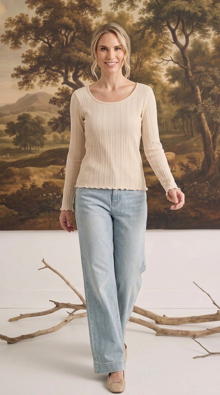 graced textured ribbed long sleeve top in beige worn by a woman with light blue jeans in a studio setting