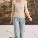 graced textured ribbed long sleeve top in beige worn by a woman with light blue jeans in a studio setting