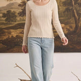 graced textured ribbed long sleeve top in beige worn by a woman with light blue jeans in a studio setting