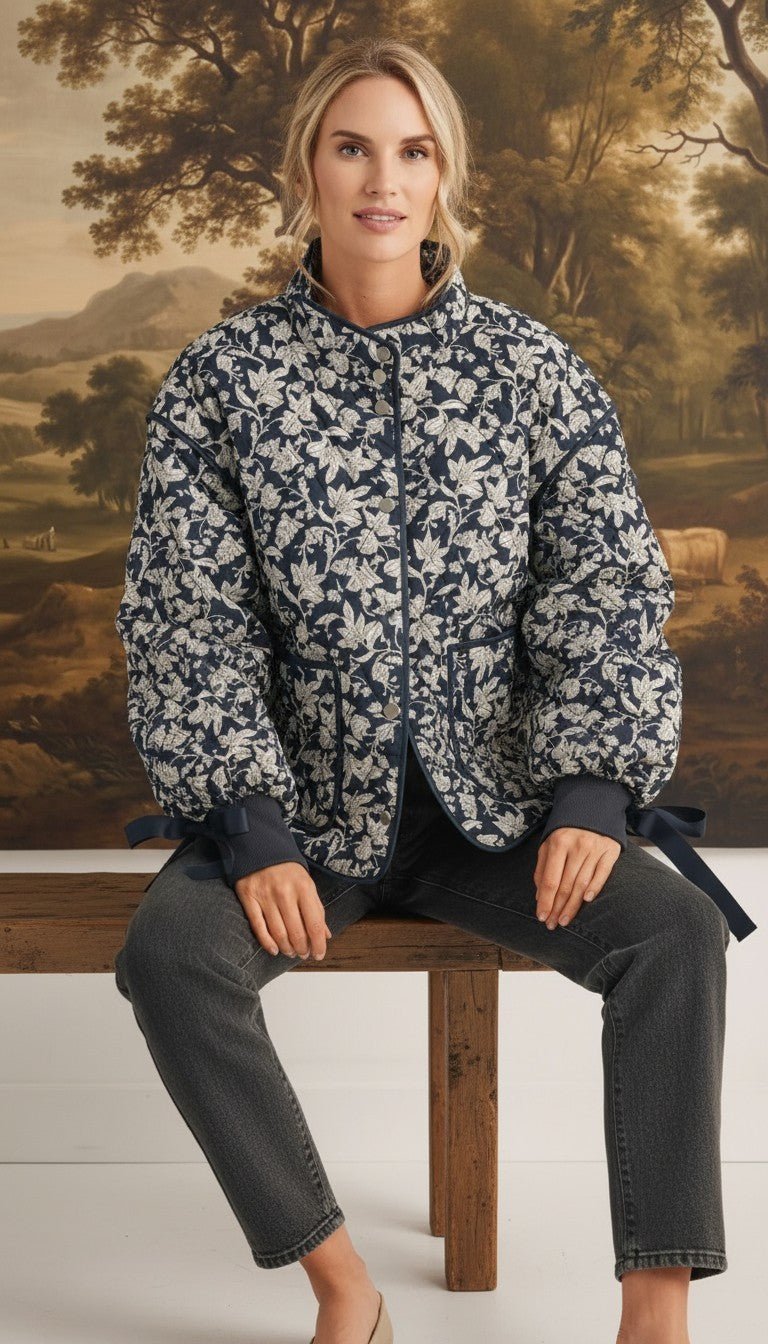 graced Alexis floral quilted cotton jacket with sleeve bows worn by a model sitting on a wooden bench
