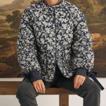 graced Alexis floral quilted cotton jacket with sleeve bows worn by a model sitting on a wooden bench