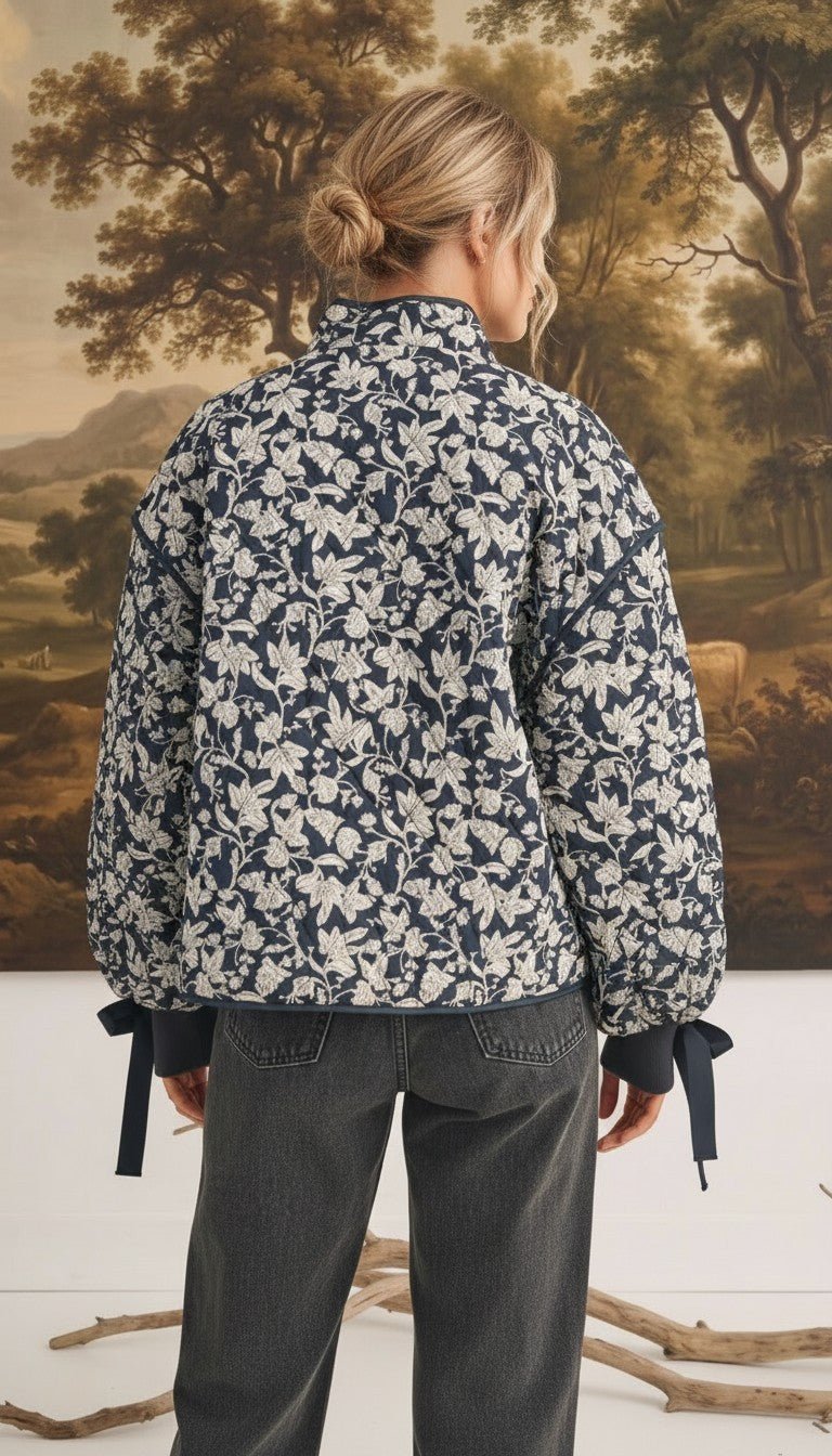 Back view of a model wearing the graced Alexis floral quilted cotton jacket with bow details on the sleeve cuffs.