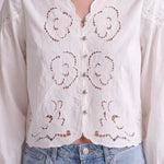 graced white cotton blend blouse featuring intricate floral embroidery and silver button front closure