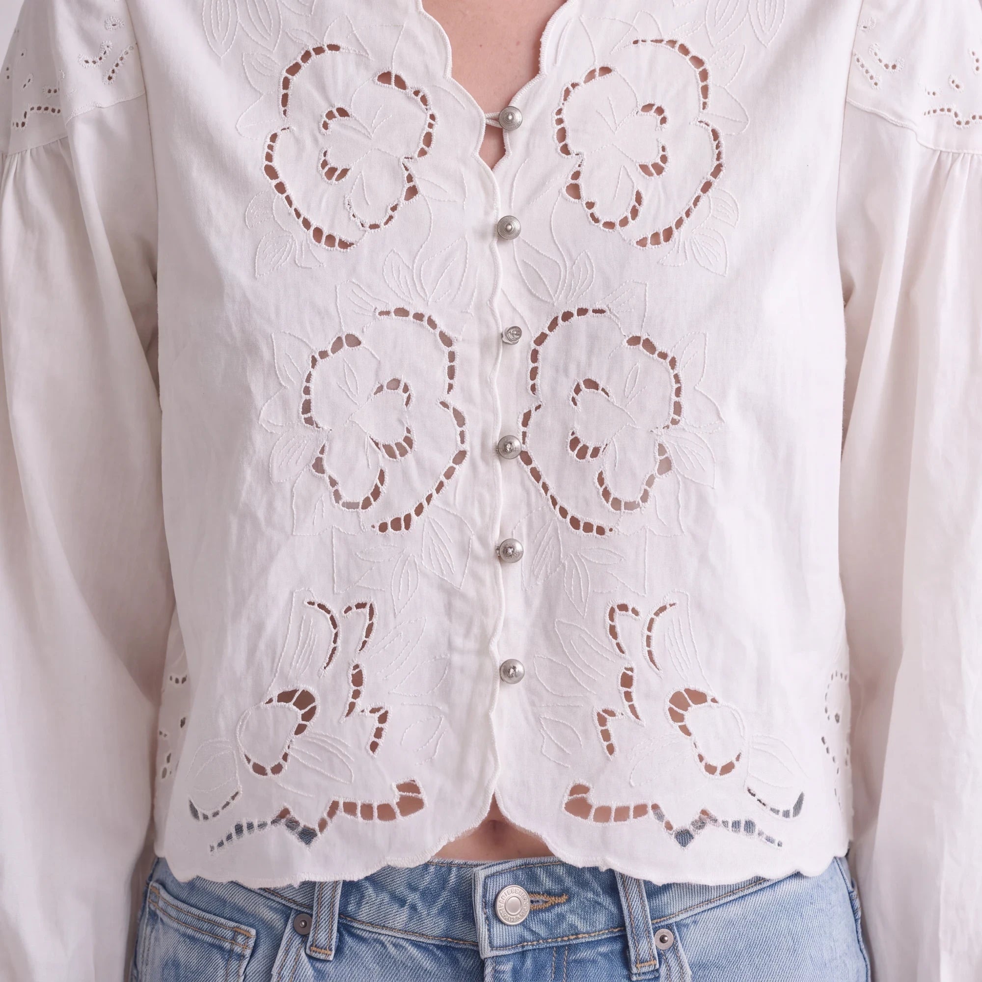 graced white cotton blend blouse featuring intricate floral embroidery and silver button front closure