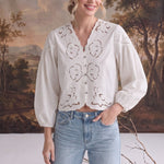 graced white cotton blend blouse with intricate floral embroidery, v-neckline, and puff sleeves worn by a model