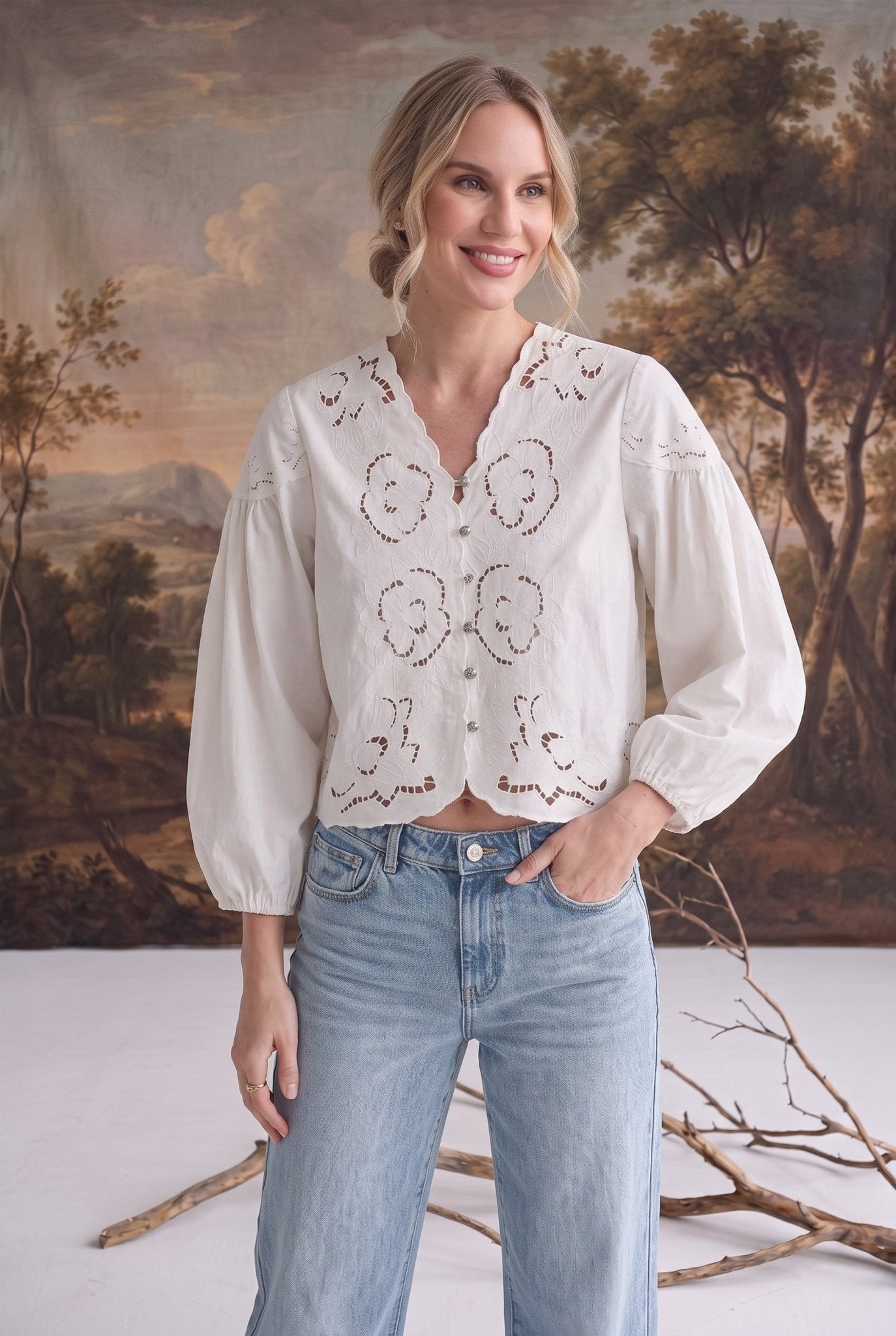 graced white cotton blend blouse with intricate floral embroidery, v-neckline, and puff sleeves worn by a model