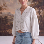 graced white April Embroidery Blouse with intricate needlework, V-neck, and puff sleeves worn with light wash jeans