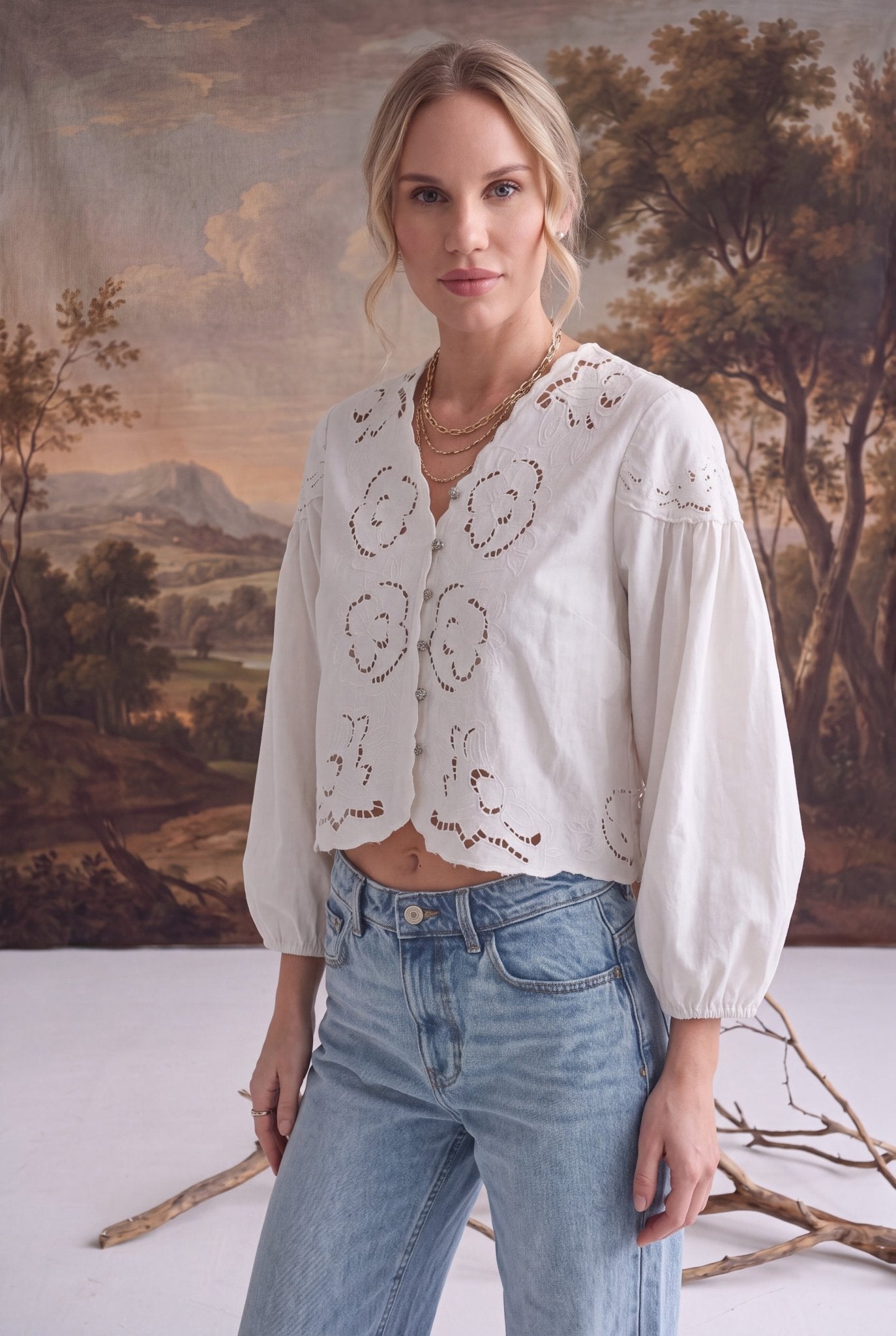 graced white April Embroidery Blouse with intricate needlework, V-neck, and puff sleeves worn with light wash jeans