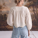Back view of a woman wearing the graced April Embroidery Blouse in cream cotton with intricate eyelet detailing.