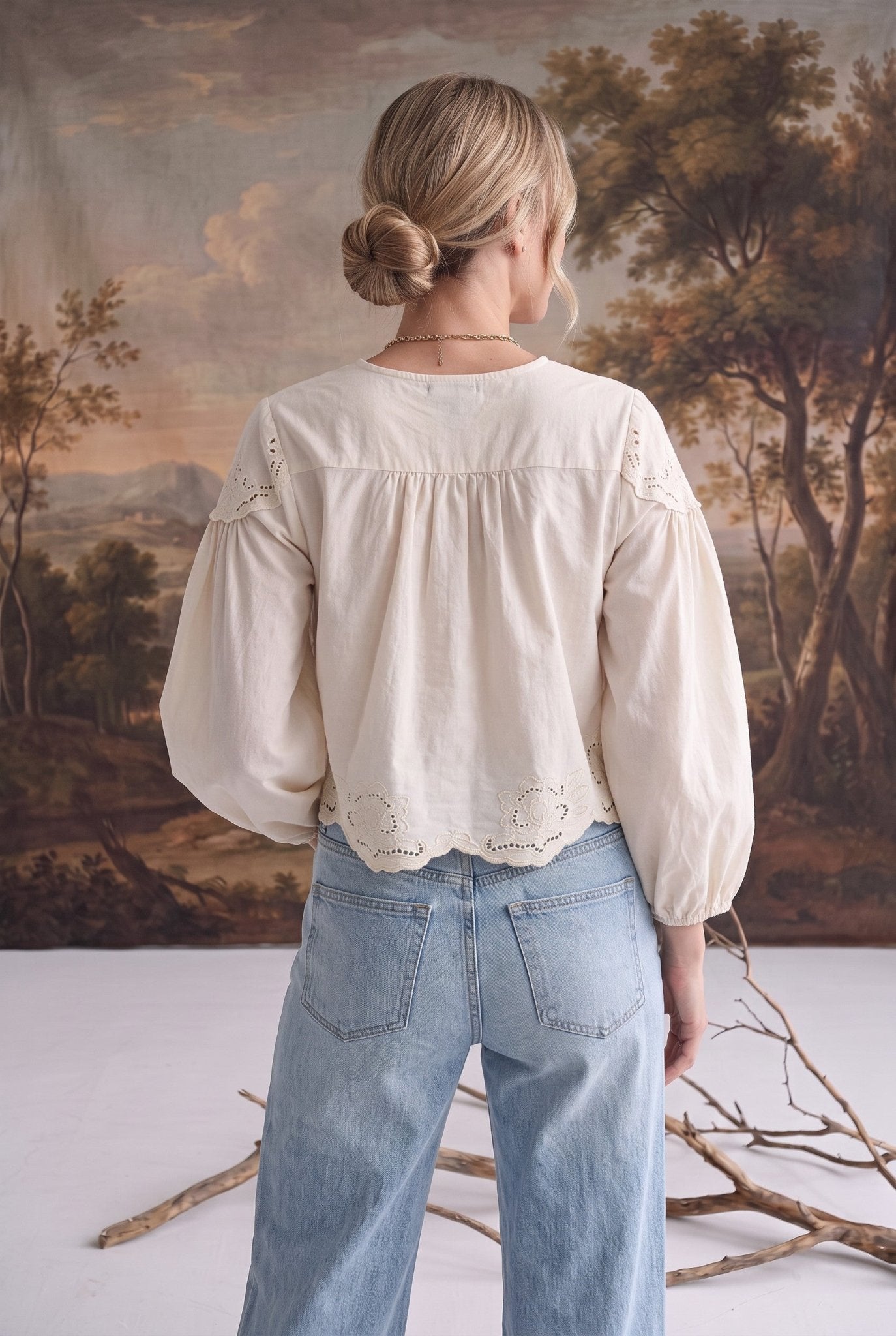 Back view of a woman wearing the graced April Embroidery Blouse in cream cotton with intricate eyelet detailing.