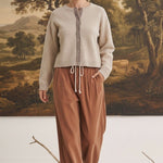 graced Baylie cardigan in beige with gingham trim worn by a model with brown corduroy pants in a studio setting