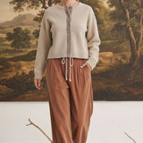 graced Baylie cardigan in beige with gingham trim worn by a model with brown corduroy pants in a studio setting