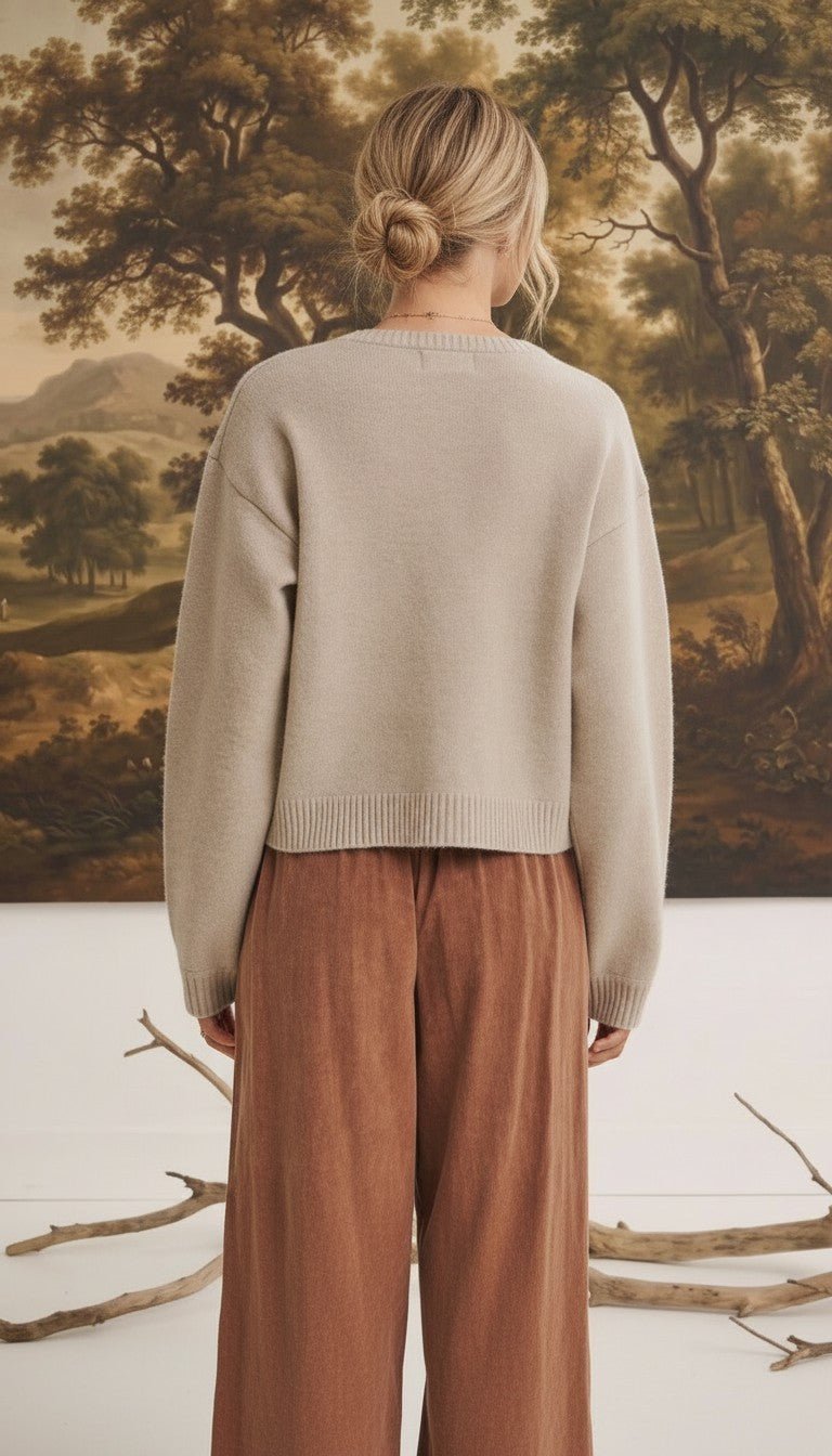 A woman wearing a beige graced Baylie cardigan from the back, featuring a ribbed hem and relaxed fit.