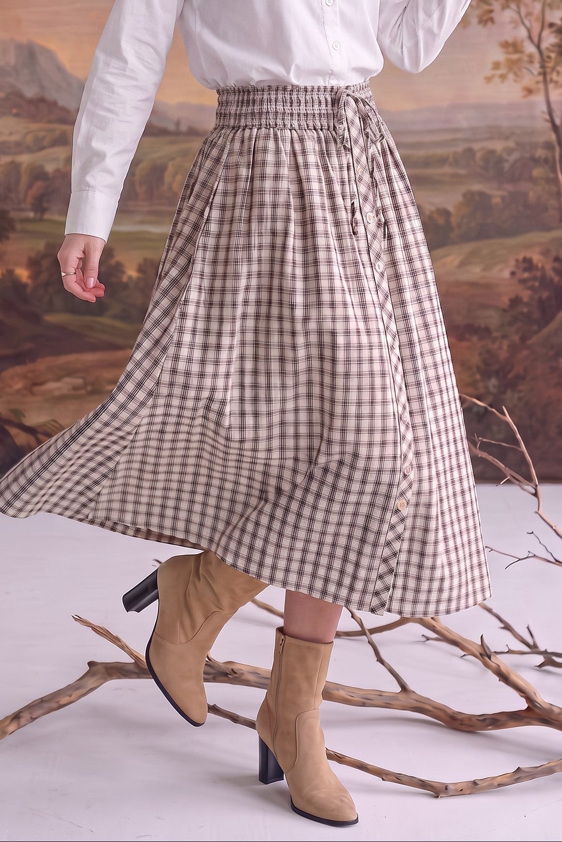 graced Beatrice plaid midi skirt with a smocked waist and button-down front, paired with tan ankle boots.