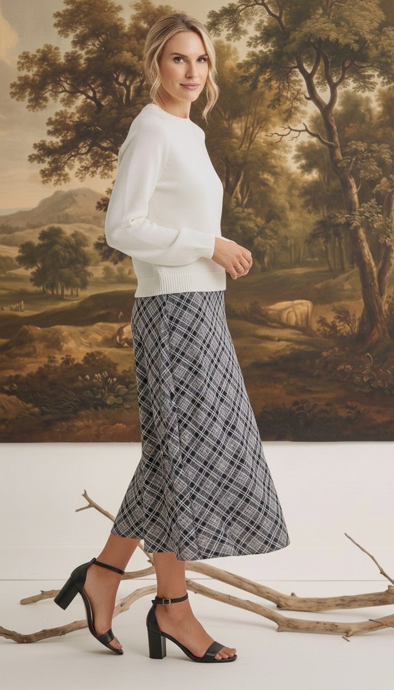 graced The Beth plaid midi skirt in black and white worn with a white sweater and black heeled sandals