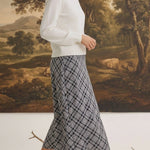 graced The Beth plaid midi skirt in black and white worn with a white sweater and black heeled sandals