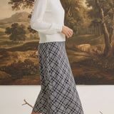 graced The Beth plaid midi skirt in black and white worn with a white sweater and black heeled sandals
