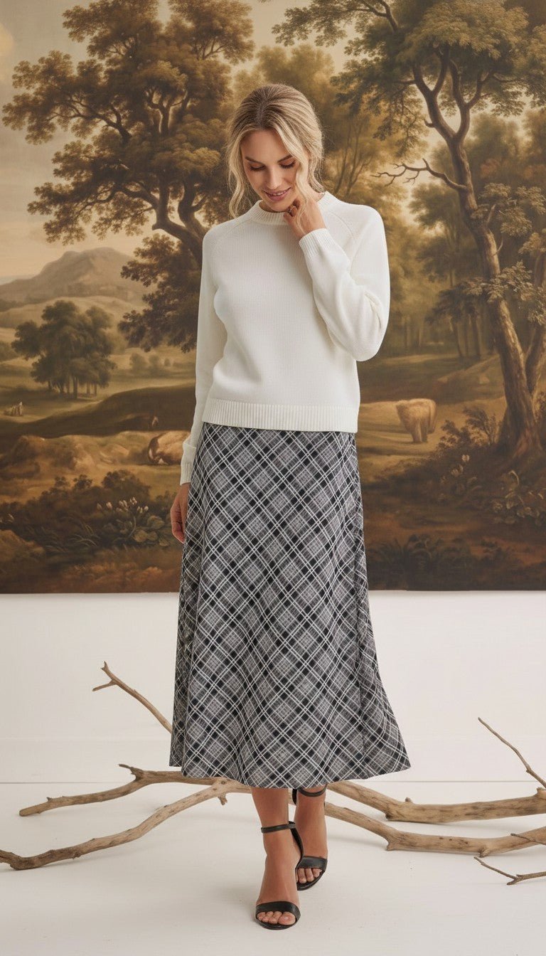 graced The Beth plaid midi skirt in black and white worn with a white sweater and black heeled sandals