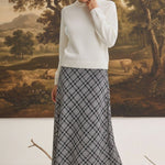 graced The Beth plaid midi skirt in black and white worn with a white sweater and black heeled sandals