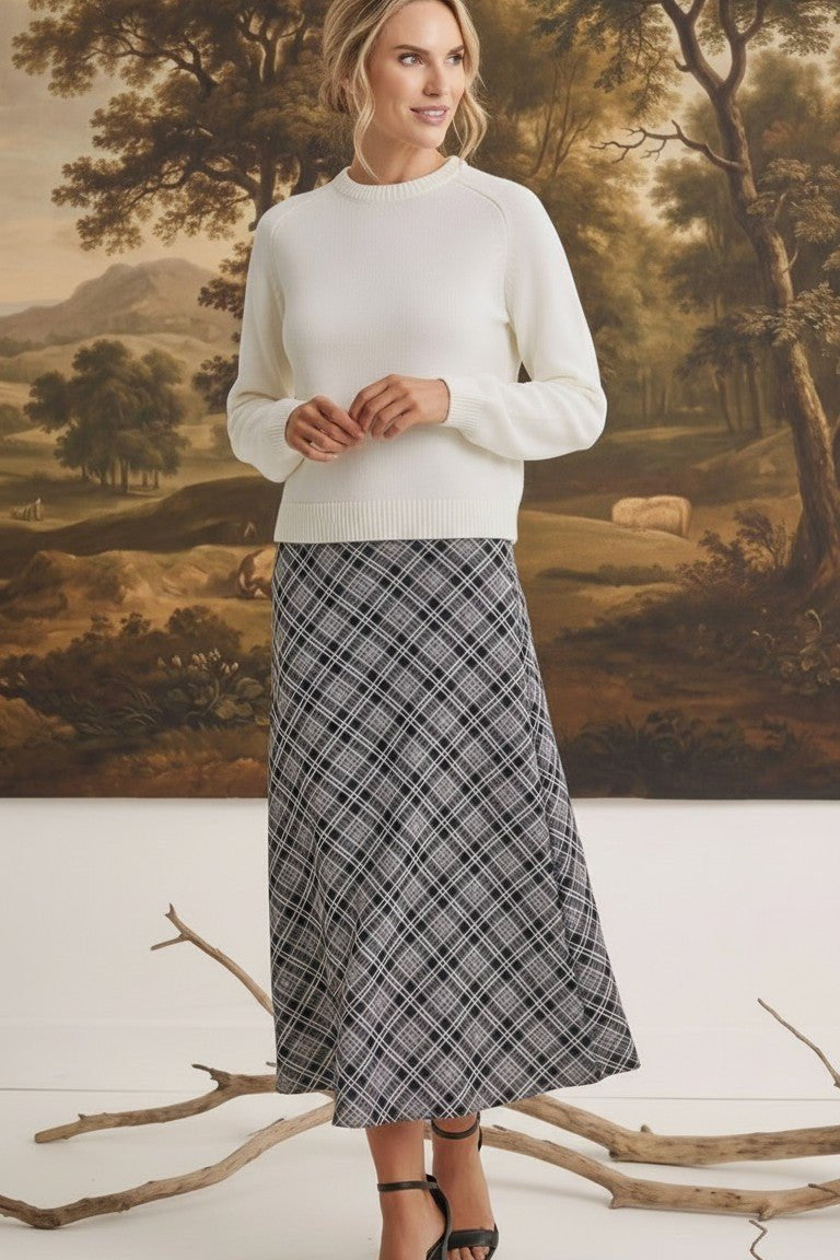 graced The Beth plaid midi skirt in black and white worn with a cream sweater by a model in a studio setting