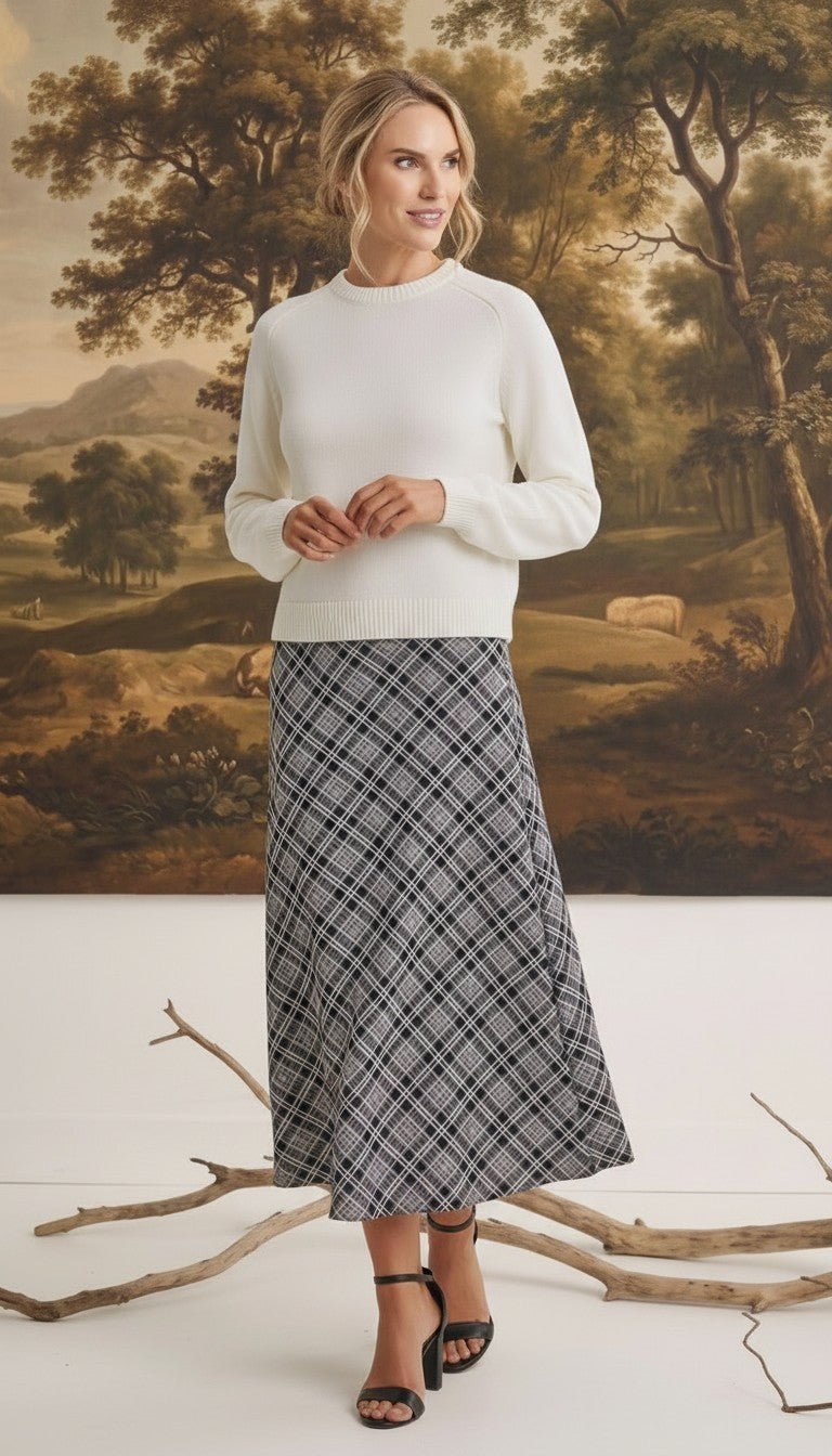 graced The Beth plaid midi skirt in black and white worn with a cream sweater by a model in a studio setting