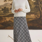 graced The Beth plaid midi skirt in black and white worn with a cream sweater by a model in a studio setting