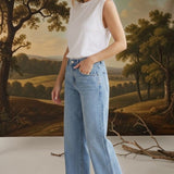 A woman wearing graced Blaine high rise straight leg jeans in a light blue wash with a white sleeveless top.