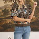 Model wearing graced brown floral top with puff sleeves and ribbed waist, styled with blue jeans.