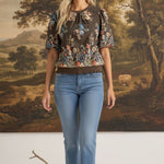 graced Brenda floral top in brown with puff sleeves and embroidered details worn by a blonde model with blue jeans