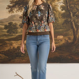 graced Brenda floral top in brown with puff sleeves and embroidered details worn by a blonde model with blue jeans